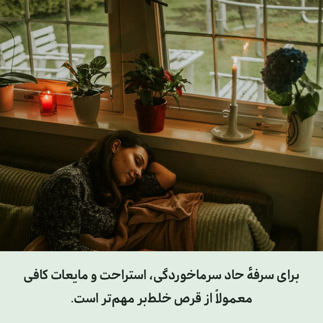 زنی که با پتو روی کاناپه کنار پنجره استراحت می‌کند