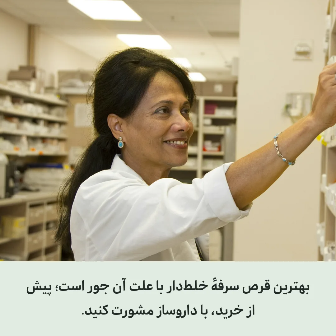 داروساز با روپوش سفید در حال برداشتن دارو از قفسهٔ داروخانه