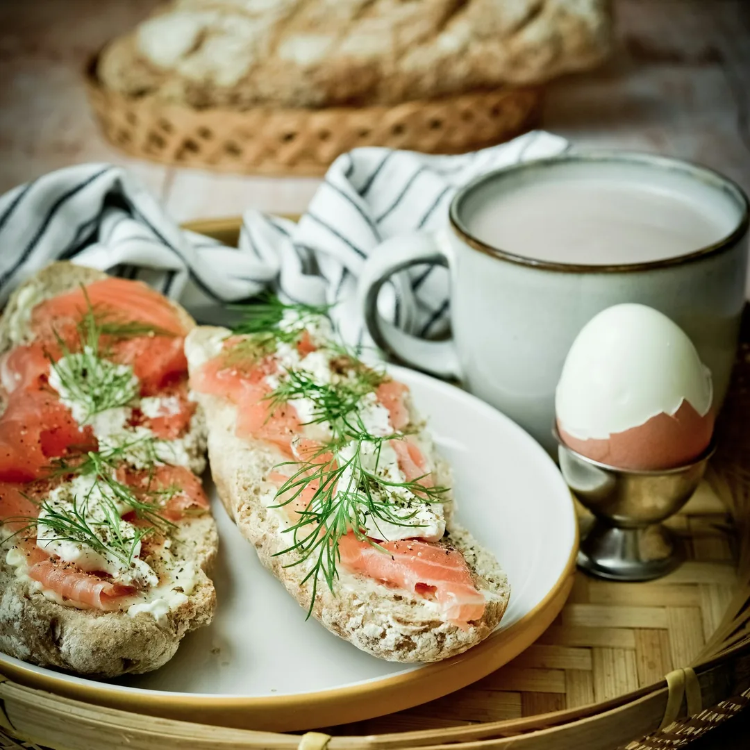 نان تست با ماهی سالمون دودی، یک تخم‌مرغ آب‌پز و فنجان شیر روی سینی